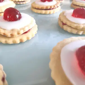 Empire German biscuit cookie with raspberry jam icing and cherry on top
