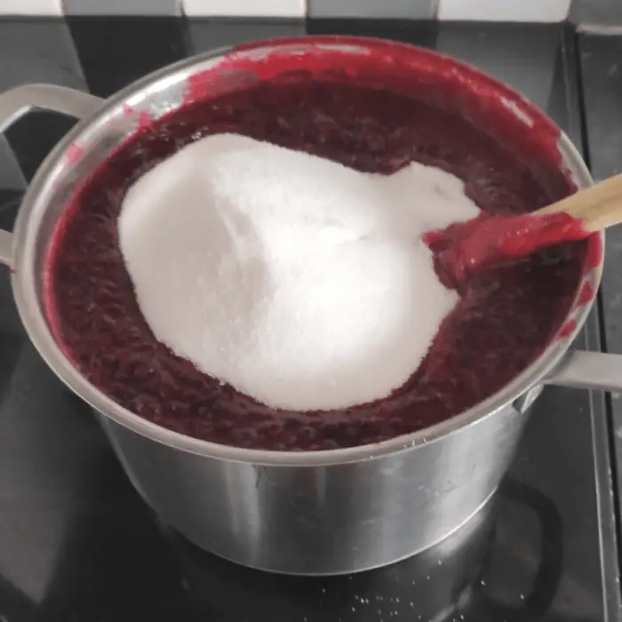 adding granulated sugar to the jam making pot