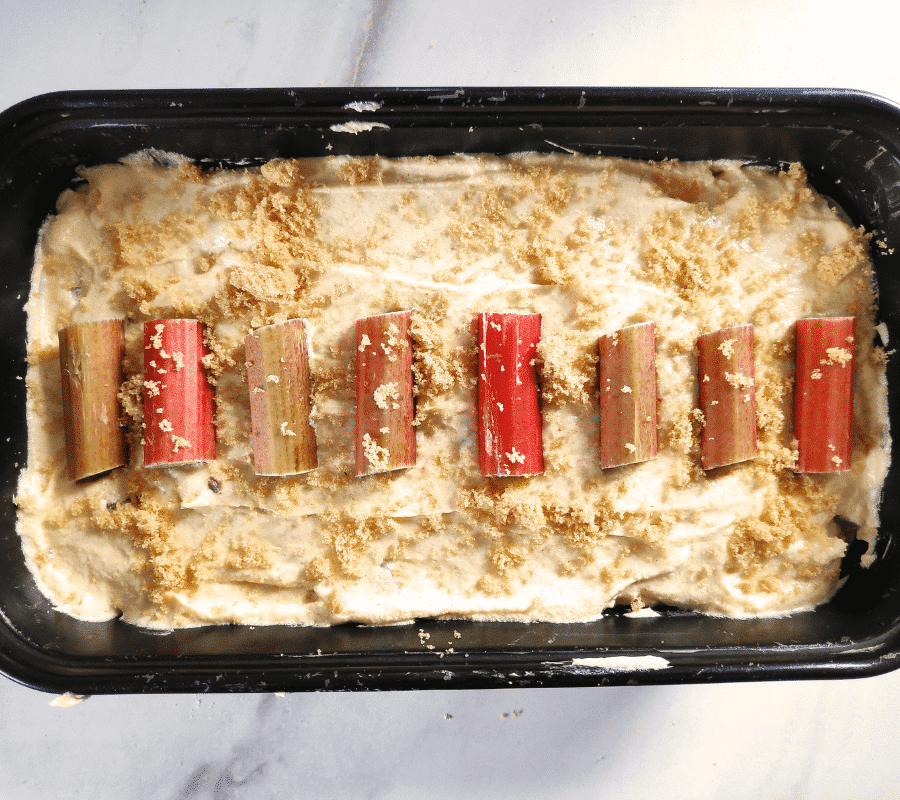 ginger and rhubarb mixture in baking loaf tin topped with rhubarb