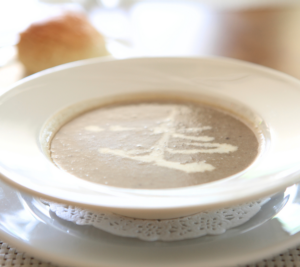 mushroom soup in a white bowl with a splash of cream