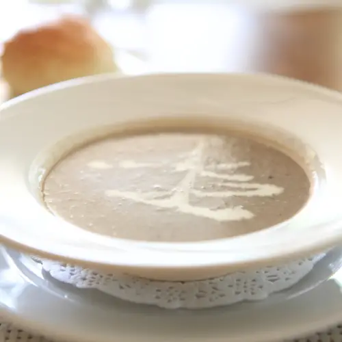 mushroom soup in a white bowl with a splash of cream