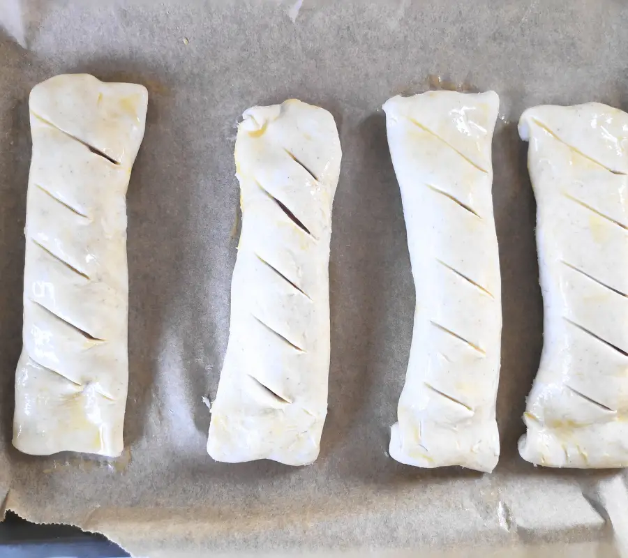 raw sausages wrapped in puff pastry before baking