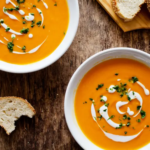 2 bowls of pumpkin soup with spinach and cream swirls in it uk recipe