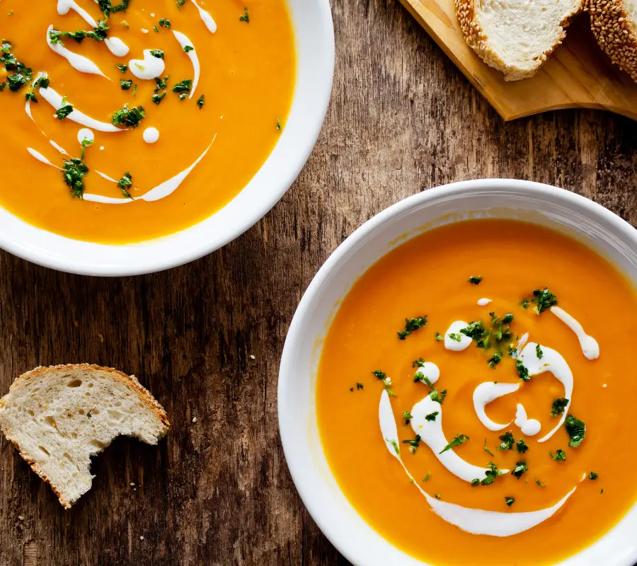 2 bowls of pumpkin soup with spinach and cream swirls in it uk recipe