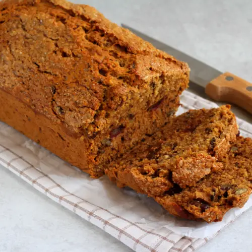 date and walnut cake loaf on a napkin with knife at the side