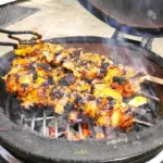 three pork kebabs cooking on a kamado