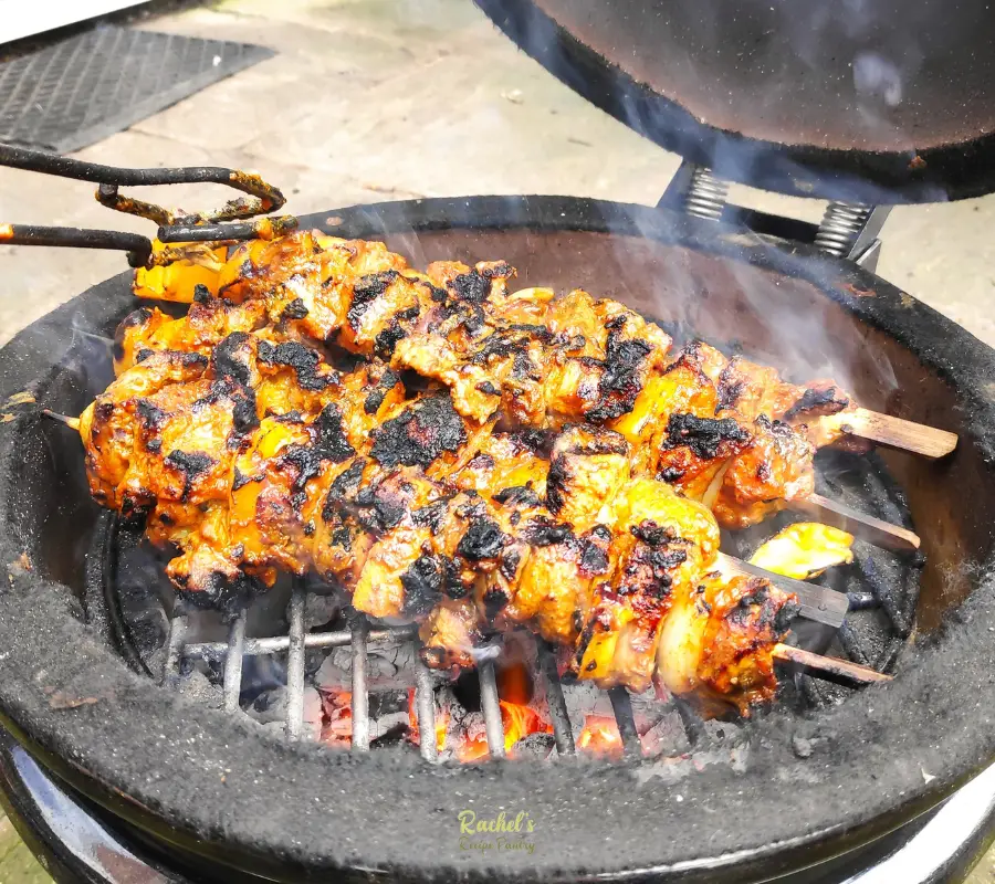 three pork kebabs cooking on a kamado