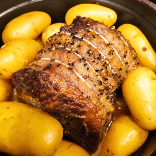 cooked beef brisket in a oven proof dish surrounded by small potatoes