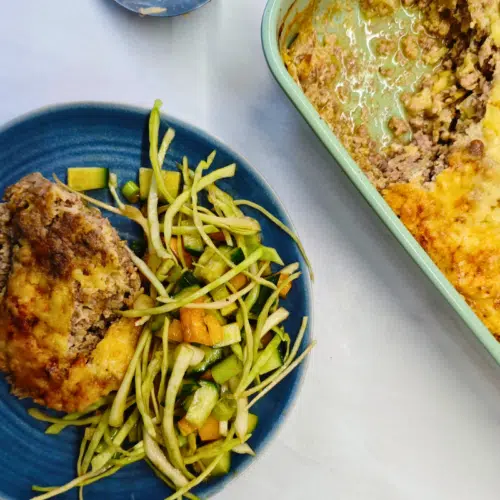 a portion of gluten free meat pie on a blue plate with salad