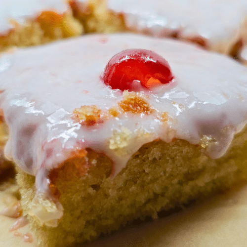 close up of a square piece of cherry bakewell cake from a traybake recipe