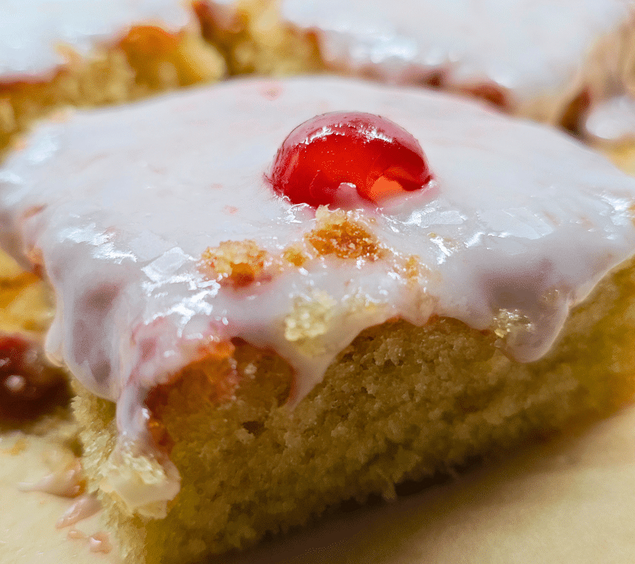 close up of a square piece of cherry bakewell cake from a traybake recipe