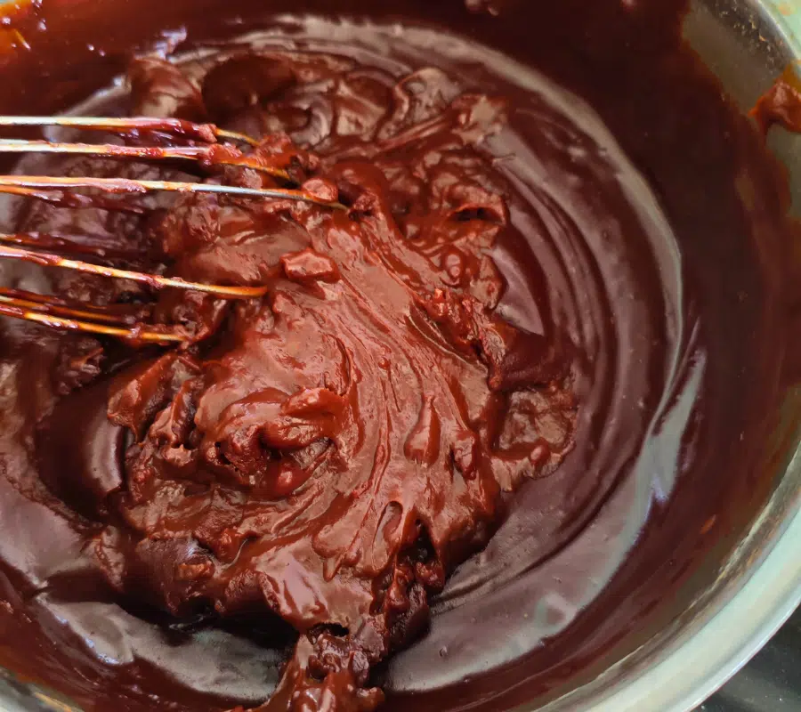 chocolate custard cake topping in a stainless steel pan