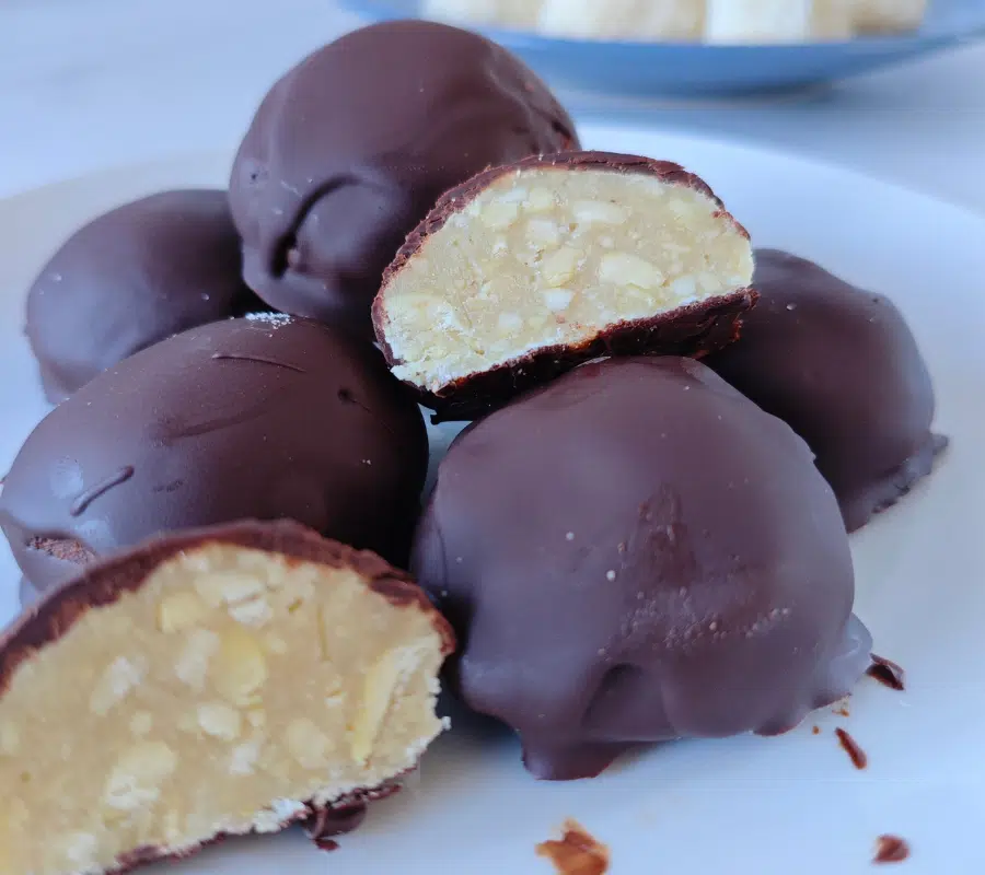 chocolate bombs on a white plate, one cut in half showing a nutty truffle centre