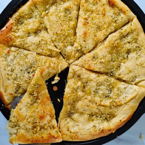 freshly made pizza garlic bread on a pizza tray all sliced ready to eat