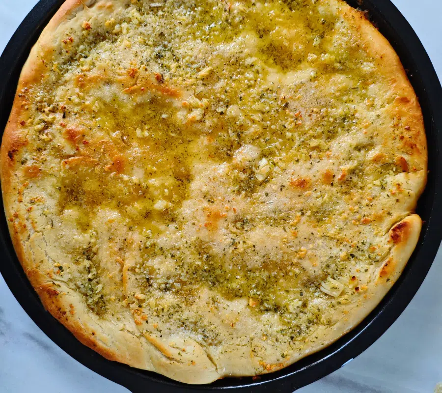 fresh garlic pizza bread on a pizza baking tray uncut