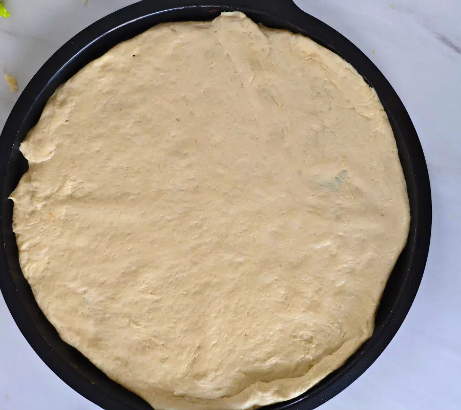 garlic bread dough rolled out as a pizza shape laid on a pizza baking tray