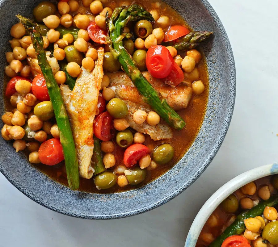 pollock fish in a bowl with chickpeas, asparagus, cherry tomatoes and olives
