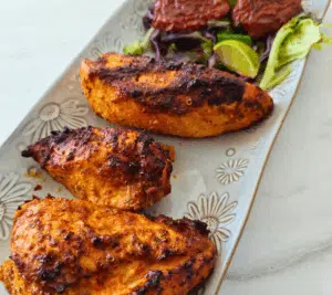 peri peri chicken breasts on a white long plate. A variety of healthy chicken breast recipes from Rachel's Recipe Pantry.