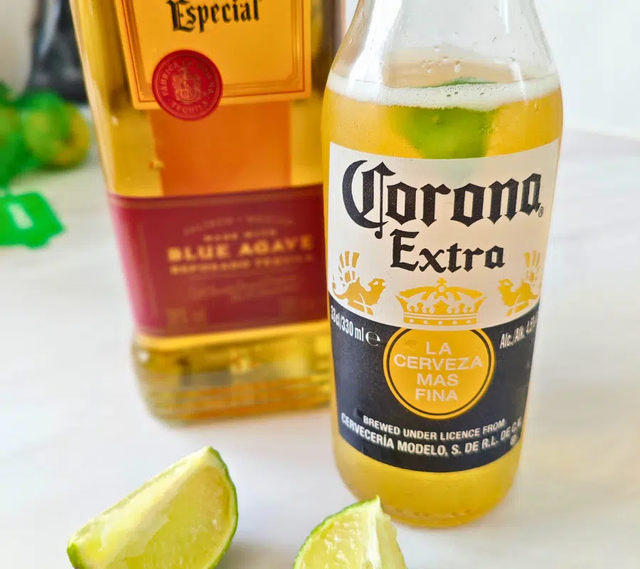 a bottle of corona, tequila and sliced limes