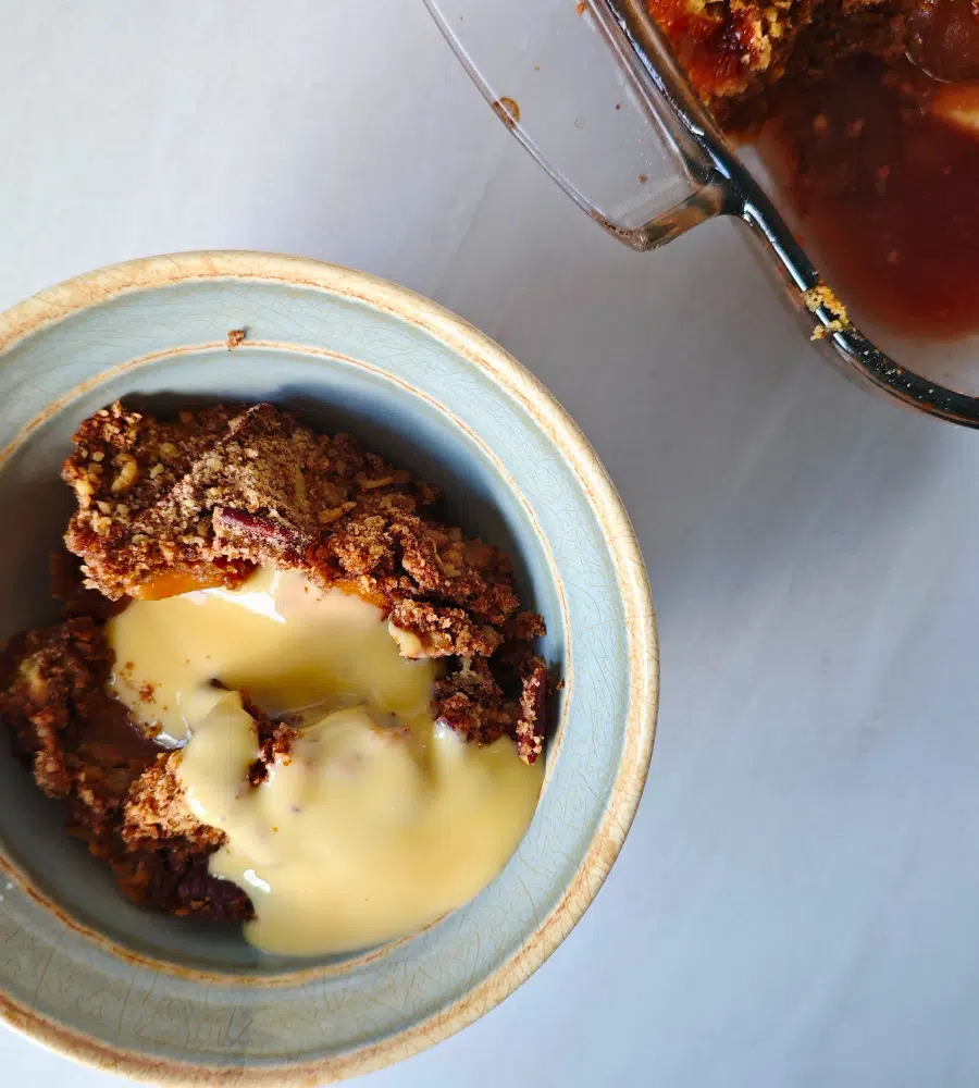 apple and plum crumble with custard in a bowl