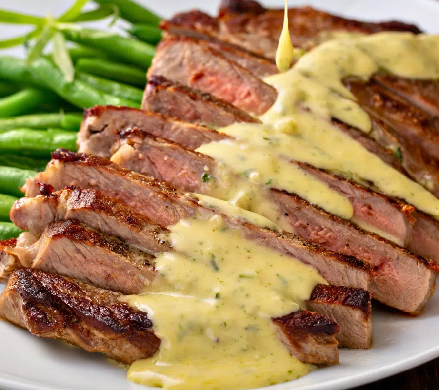 bearnaise sauce on top of sliced steak