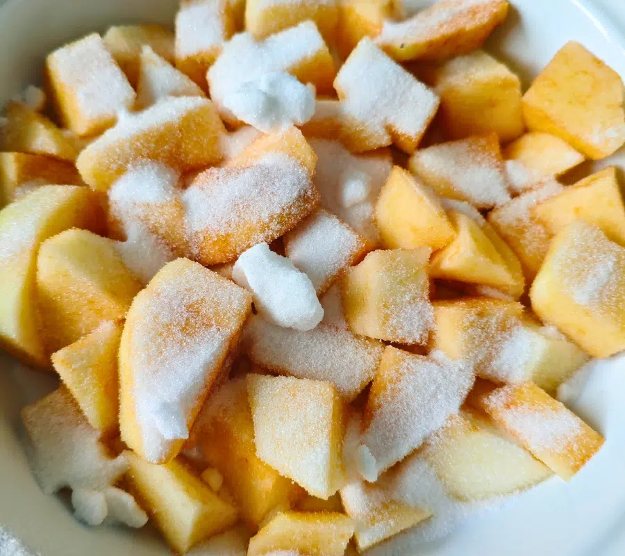 chopped apples in a white oven proof dish top with sugar and nutmeg