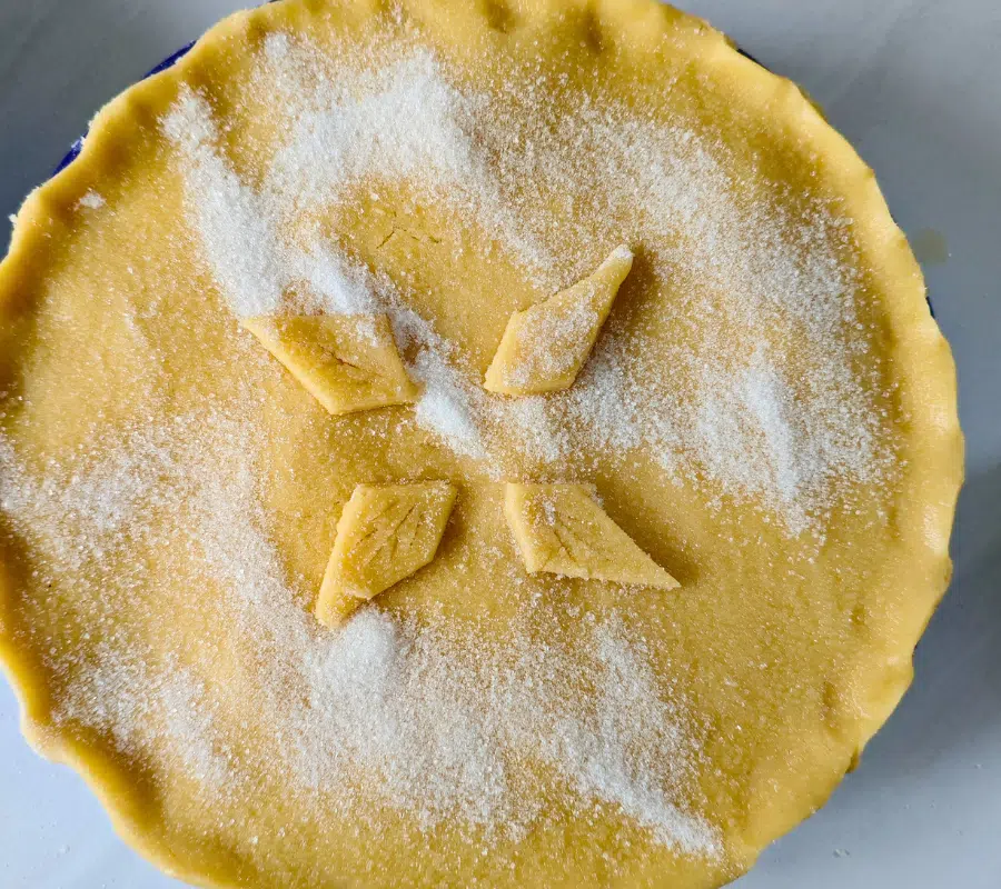 birds eye view of apple pie before it's baked topped with granulated sugar