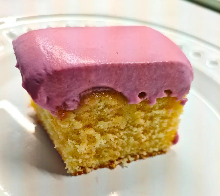 a slice of vanilla sponge traybake topped with a light mousse-like blackcurrant yoghurt whip