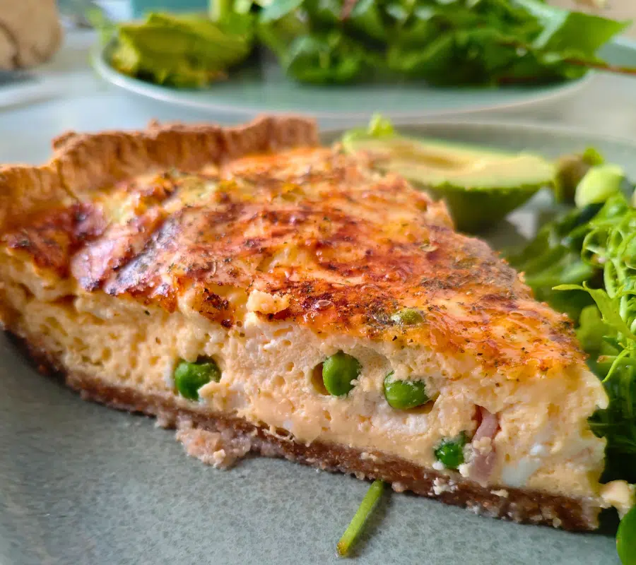 pea and bacon quiche on a plate with salad