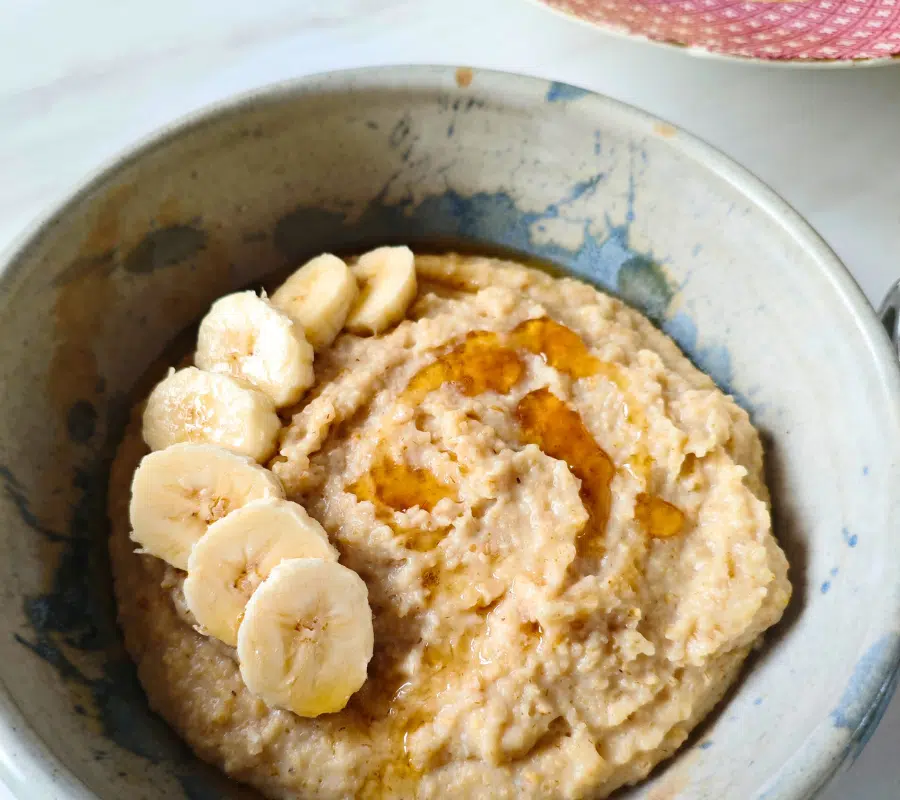 egg porridge in a bowl topped with sliced banana and a drizzle of syrup