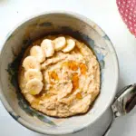 egg porridge in a bowl topped with sliced banana and a drizzle of syrup