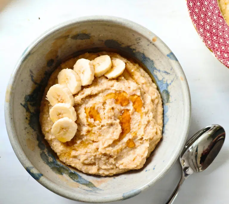 egg porridge in a bowl topped with sliced banana and a drizzle of syrup